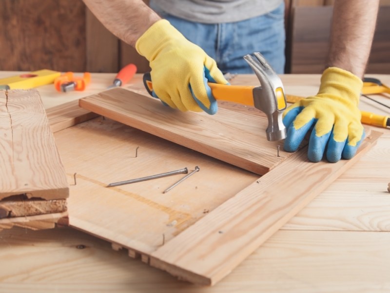 Ein Handwerker hämmert Nägel in ein Brett.