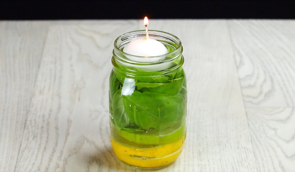 Eine selbstgemachte Mückenkerze aus Limette, Basilikum und Zitrone in einem Einmachglas.