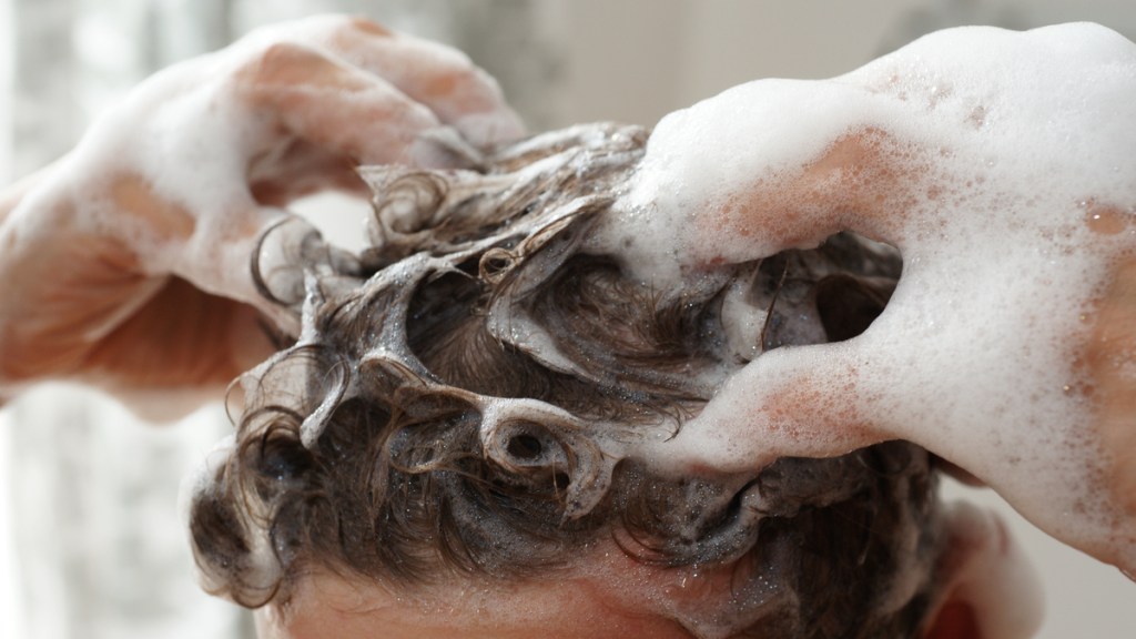 Jemand massiert seine Haare mit Shampoo ein.
