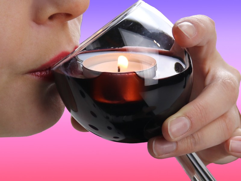 Eine Frau trinkt Wein aus einem Glas, in das ein Teelicht gephotoshopt wurde