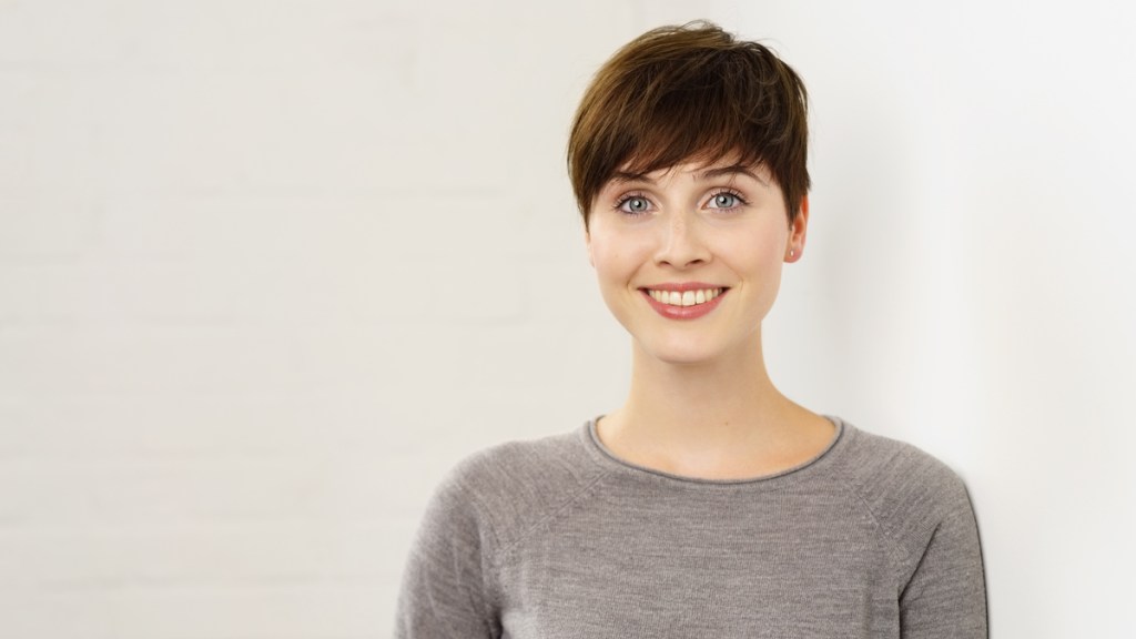 Eine Frau mit kurzen braunen Haaren lächelt in die Kamera.