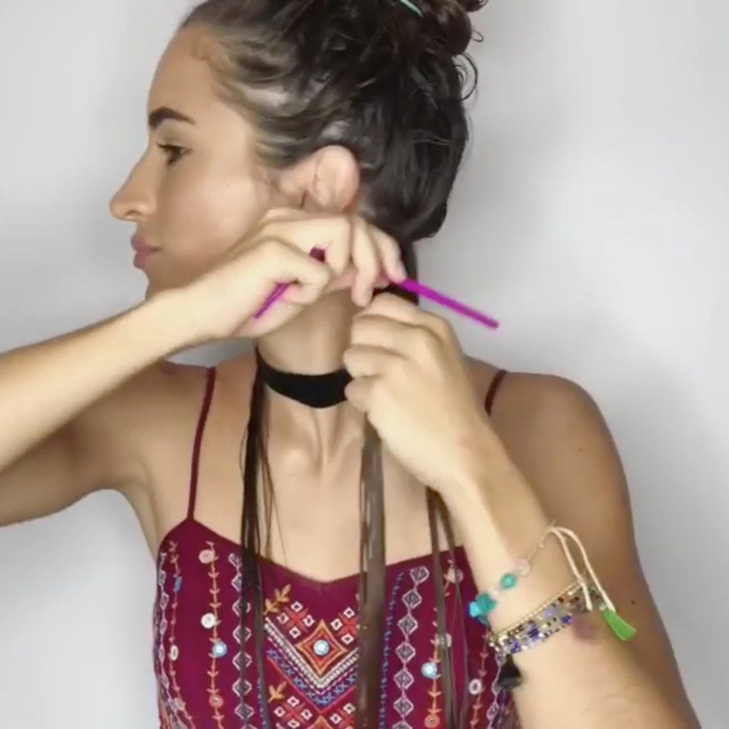 Eine Frau wickelt einen pinken Strohhalm in ihre Haare.