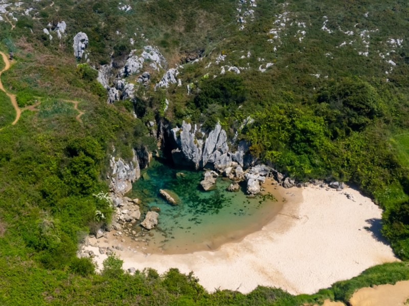 Ein Foto von einem kleinen Strand in einer Bucht, aus der Luft geschossen.