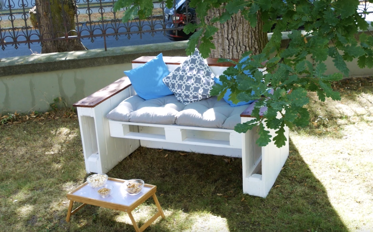 Ein Gartensofa aus Paletten steht in einem Garten.