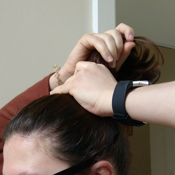 Eine Frau bindet sich ihre Haare zu einem Pferdeschwanz.
