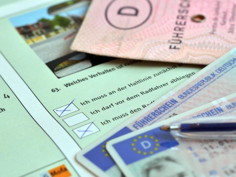 Ein Führerschein liegt auf einem Prüfungsbogen für eine Fahrschulprüfung.
