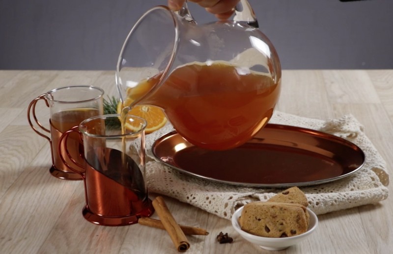 Der dunkle Tee wird aus einer Glaskanne in zwei kleine Teegläser gegossen.