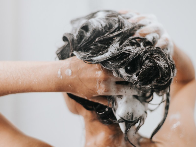 Eine Frau, die ihre Haare mit Shampoo einschäumt.
