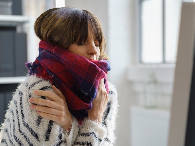 Eine Frau in Pulli und Schal friert.