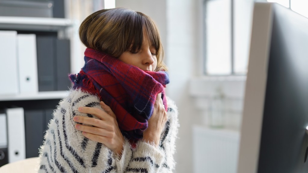 Eine Frau in Pulli und Schal friert.