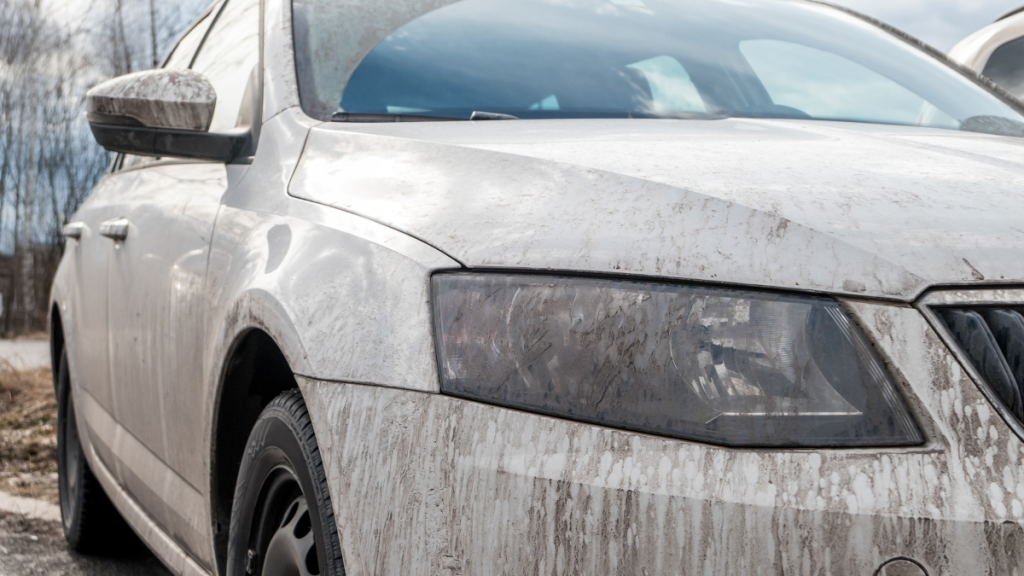 Dreckige Autoscheinwerfer eines weißen Autos.