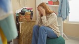 eine junge Frau sitzt vor einem vollen Wäschekorb