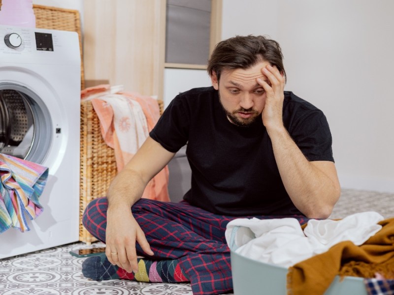 Ein Mann sitzt vor seiner Wäsche und rätselt.