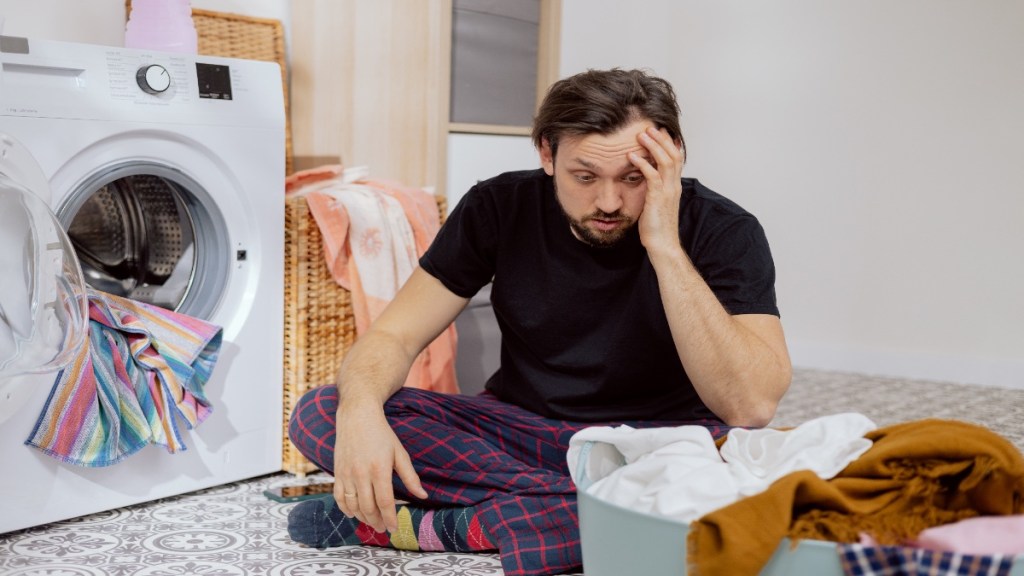 Ein Mann sitzt vor seiner Wäsche und rätselt.