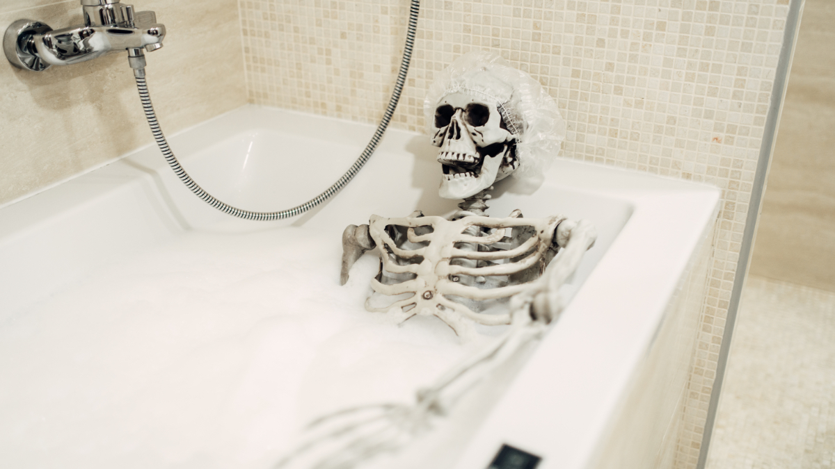 Ein gruseliges Menschen-Skelett liegt in einer mit Schaum gefüllten Badewanne.