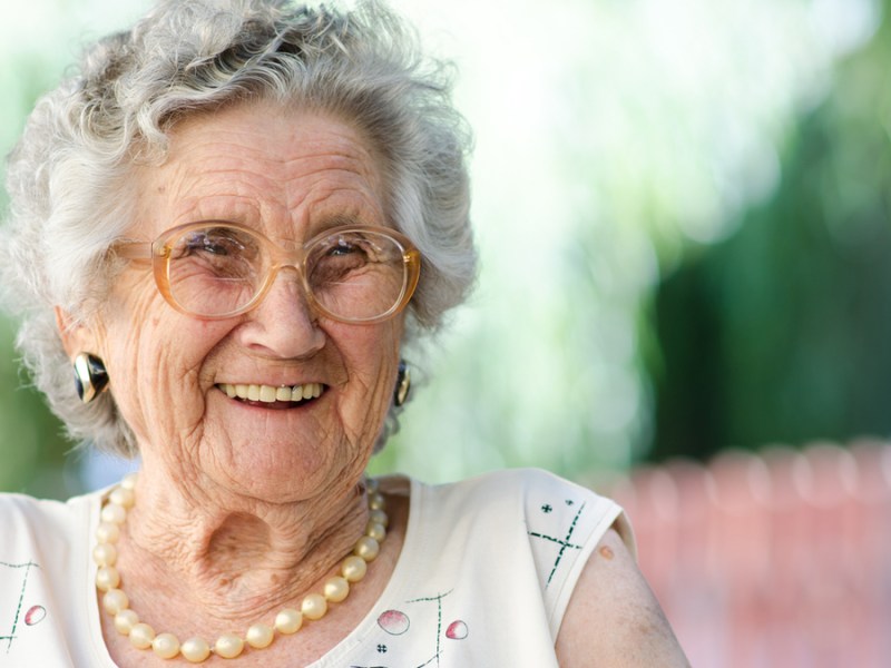 Eine ältere Frau mit grauen Haaren lächelt in die Kamera.