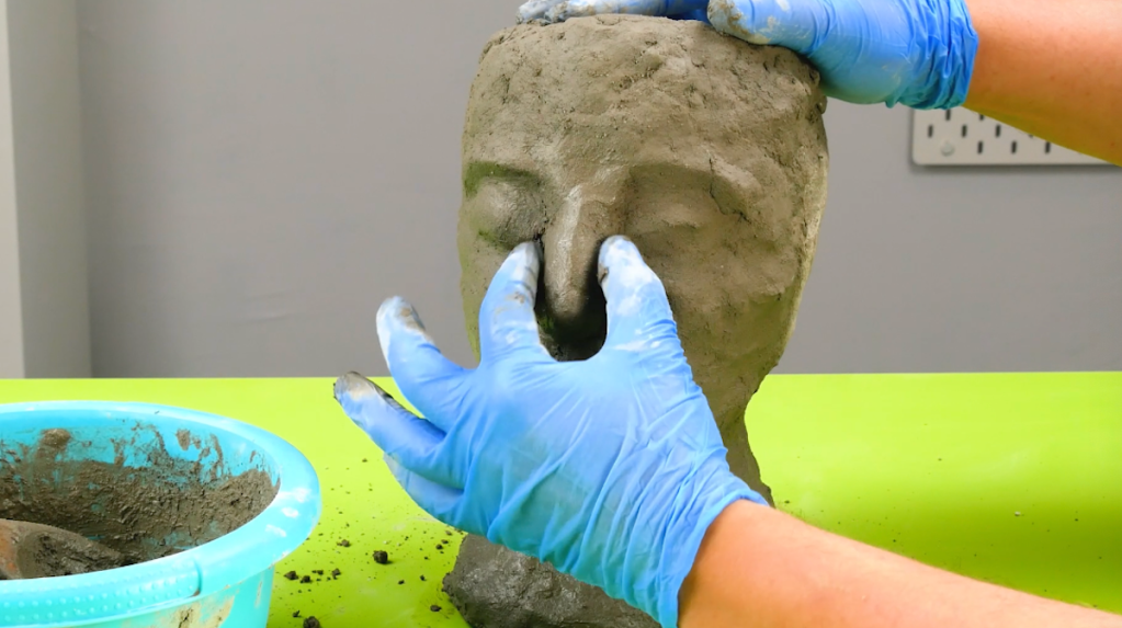 Gesichtsmerkmale werden auf dem Styroporkopf mit Zement nach gezeichnet.