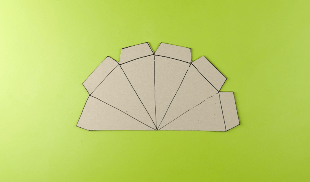 Eine Form aus Pappe vor einem hellgrünen Hintergrund.