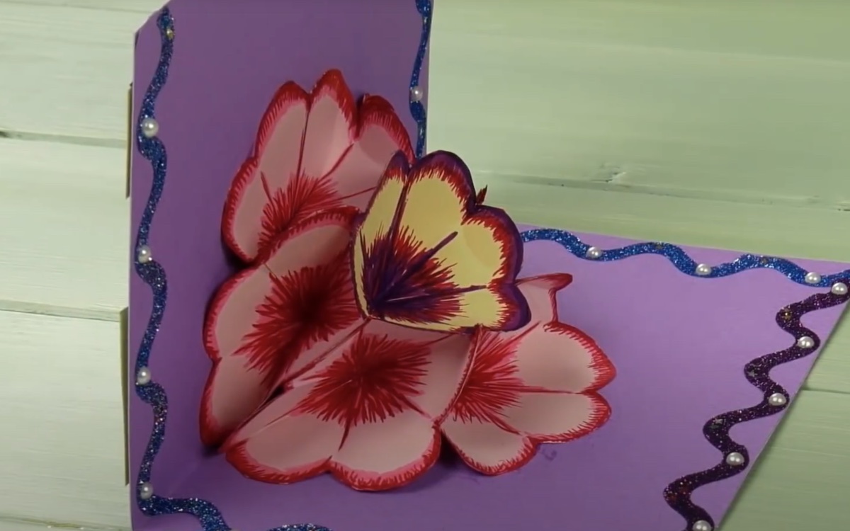 Eine aufgeklappte selbst gebastelte Geburtstagskarte mit einer Blüte aus Papier in der Mitte.