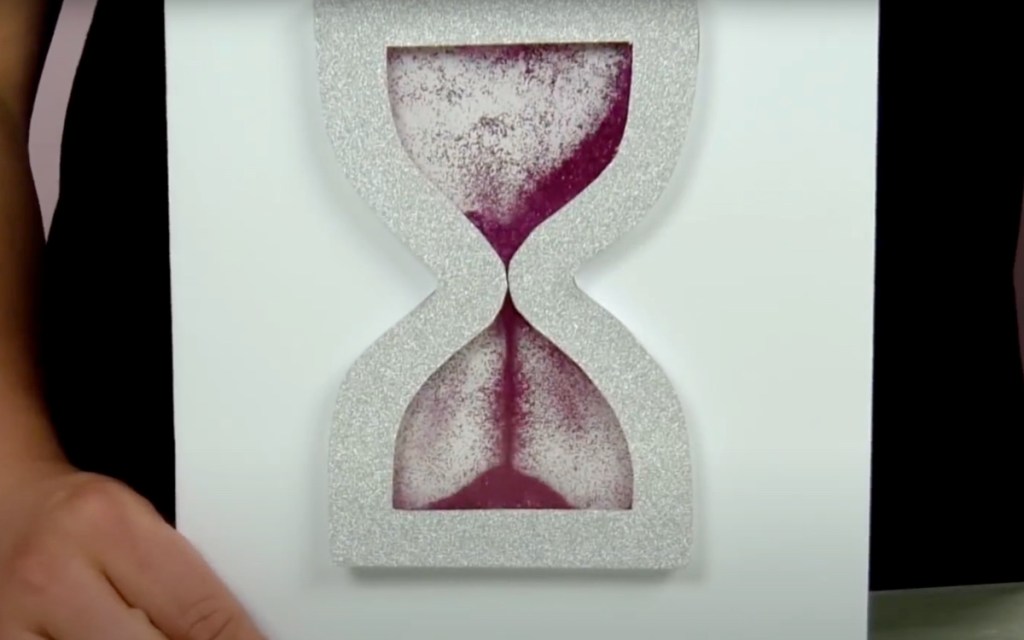 Eine Geburtstagskarte mit einer Sanduhr, durch die roter Sand läuft.