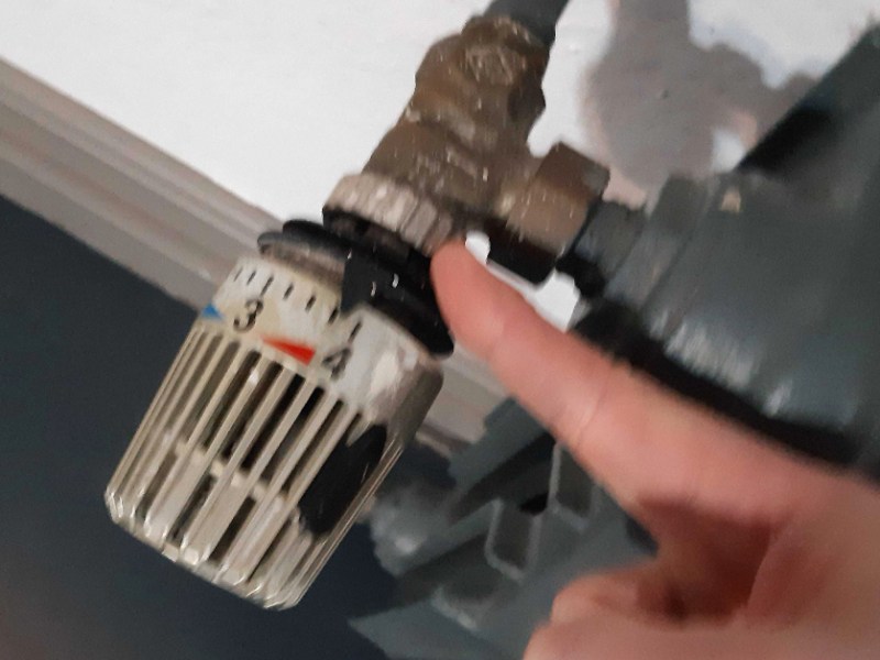 Ein Finger zeigt auf den Regler einer Heizung, der auf Stufe 4 steht.