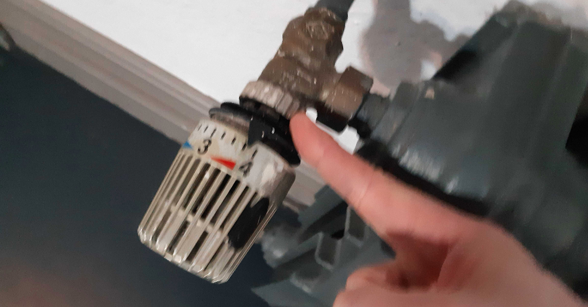 Ein Finger zeigt auf den Regler einer Heizung, der auf Stufe 4 steht.
