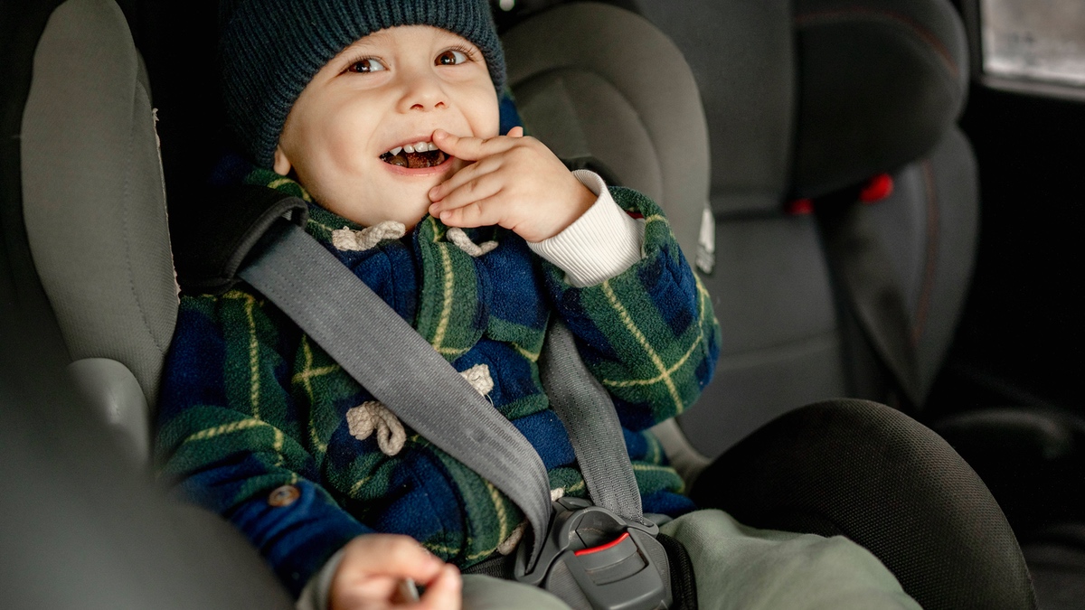 Ein Kleinkind im Autositz, der Gurt locker angelegt.