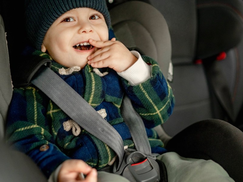 Ein Kleinkind im Autositz, der Gurt locker angelegt.