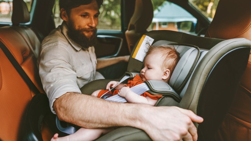 Ein Vater und sein Baby, das in einem Reboarder sitzt.