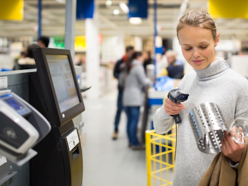 Eine Frau scannt einen IKEA-Besteckhalter an einer Self-check-out-Kasse.