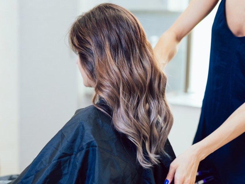 Eine Frau mit langen braunen Haaren sitzt beim Friseur.