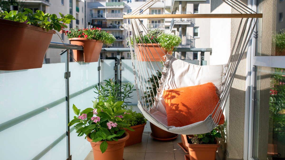 Ein Balkon mit einer Hängematte und verschiedenen Pflanzen in Töpfen.