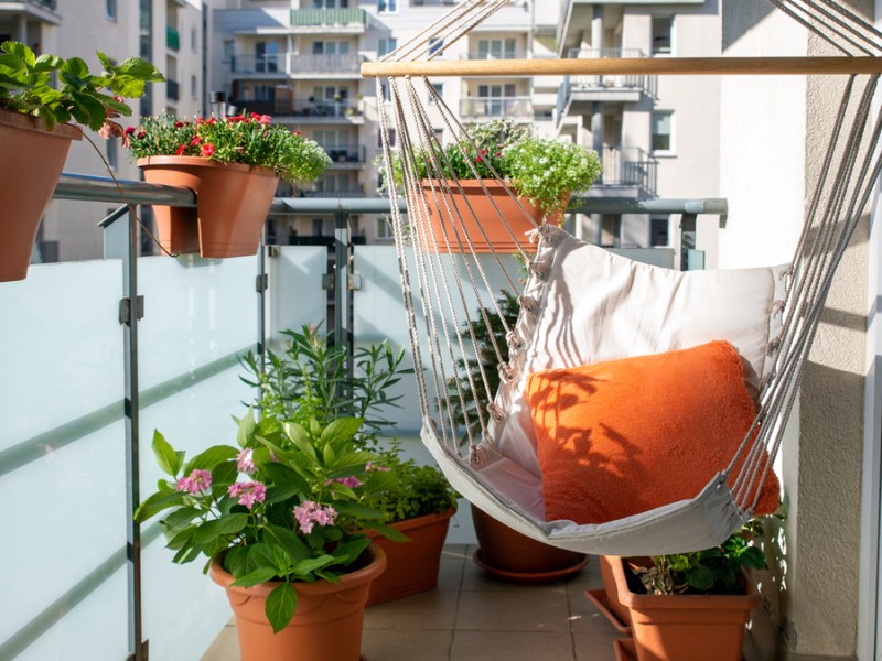 Ein Balkon mit einer Hängematte und verschiedenen Pflanzen in Töpfen.