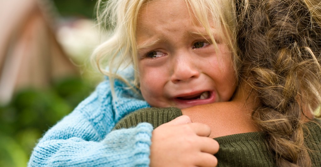 Ein Kind weint auf dem Arm einer Frau.