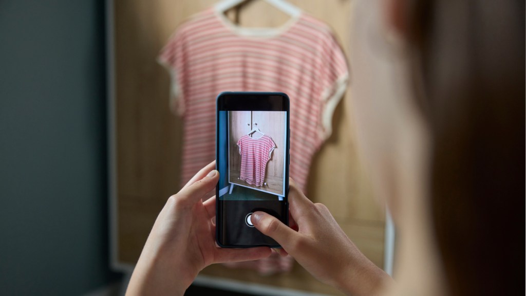 Eine Frau fotografiert ein weiteres Kleidungsstück mit dem Handy.