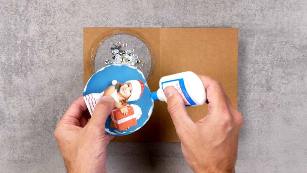 Ein Foto wird in eine selbst gebastelte Weihnachtskarte geklebt