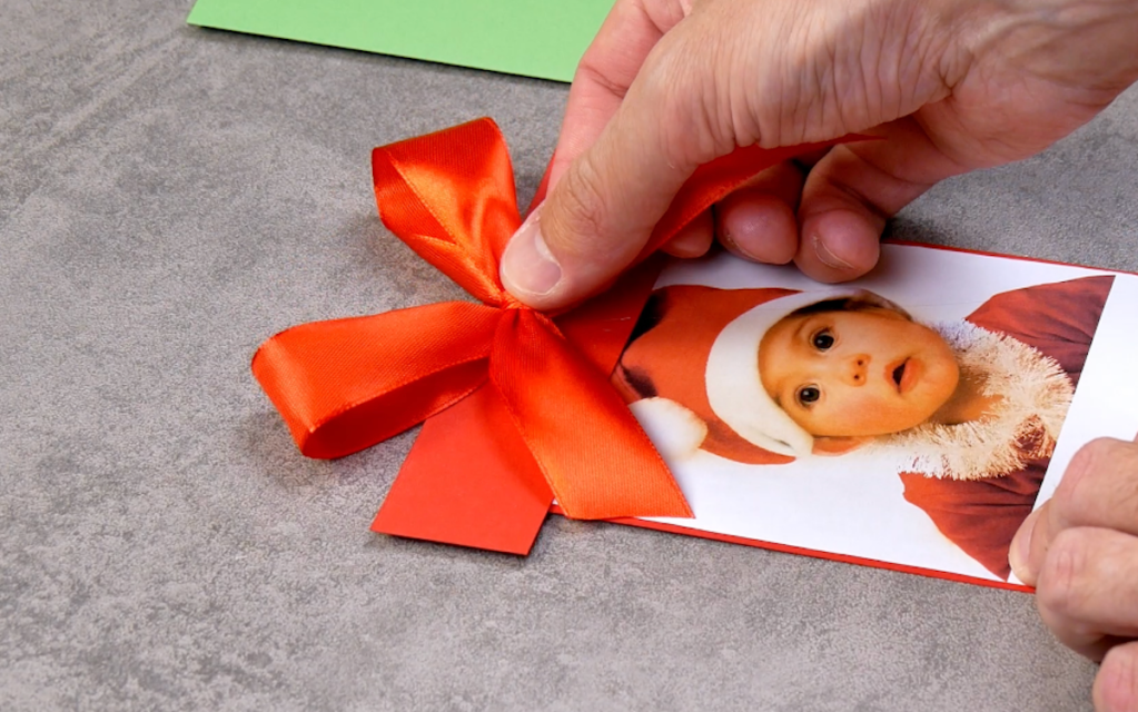 eine Schleife aus rotem Geschenkband wird auf ein Foto geklebt