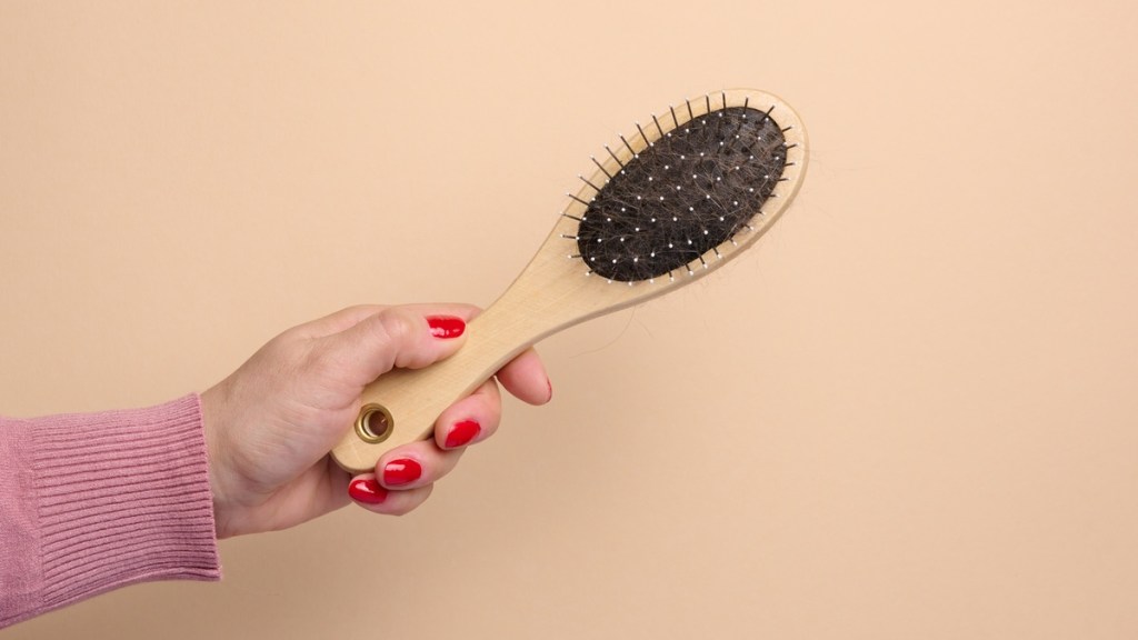 Eine Frau hält eine Haarbürste in der Hand.