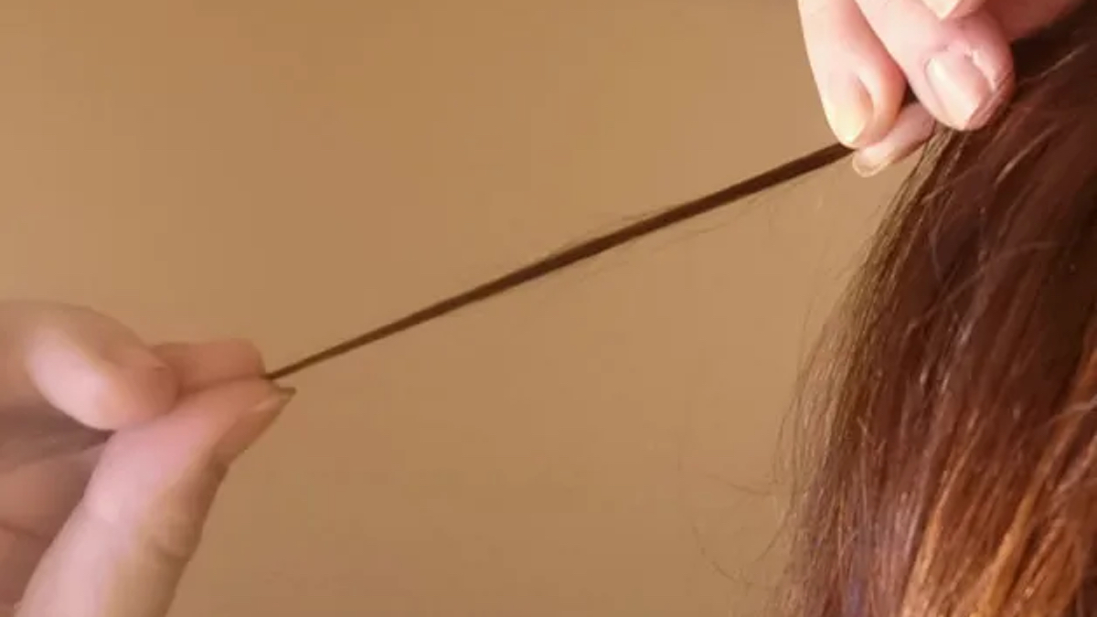 Eine Frau zwirbelt eine Haarsträhne um ihre Finger.