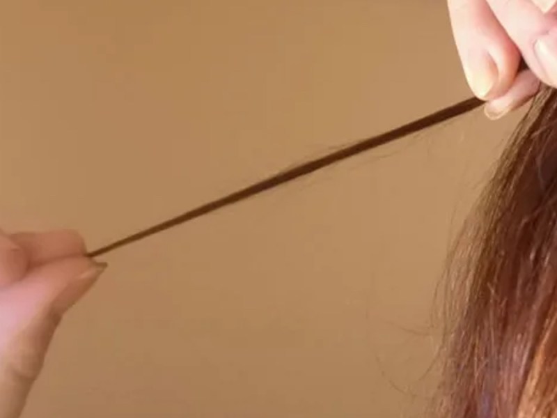 Eine Frau zwirbelt eine Haarsträhne um ihre Finger.