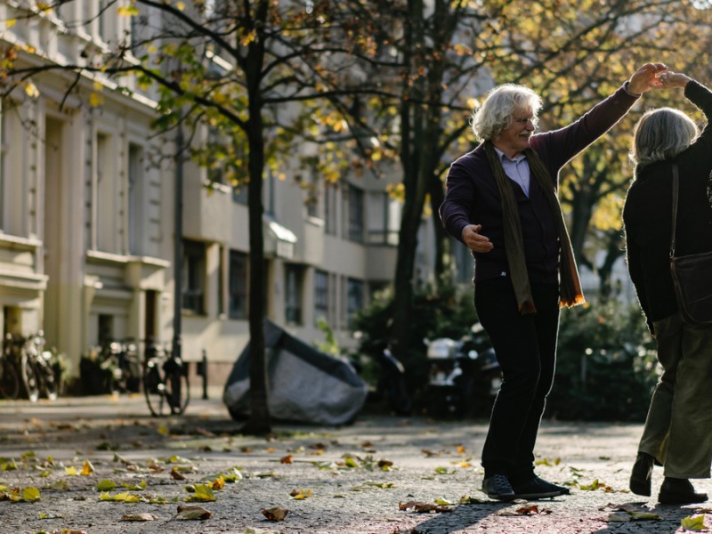 Ein älteres Pärchen tanzt in einer Straße.