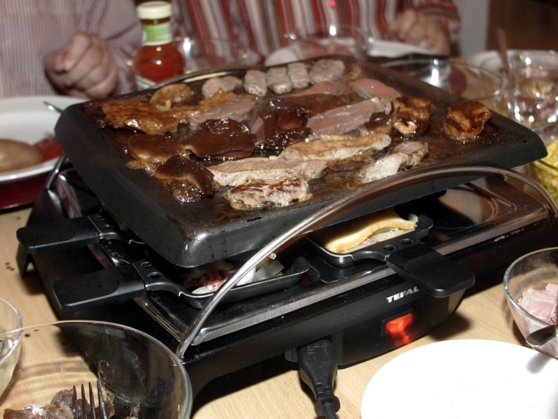 Fleisch wird auf dem Raclette gegrillt.