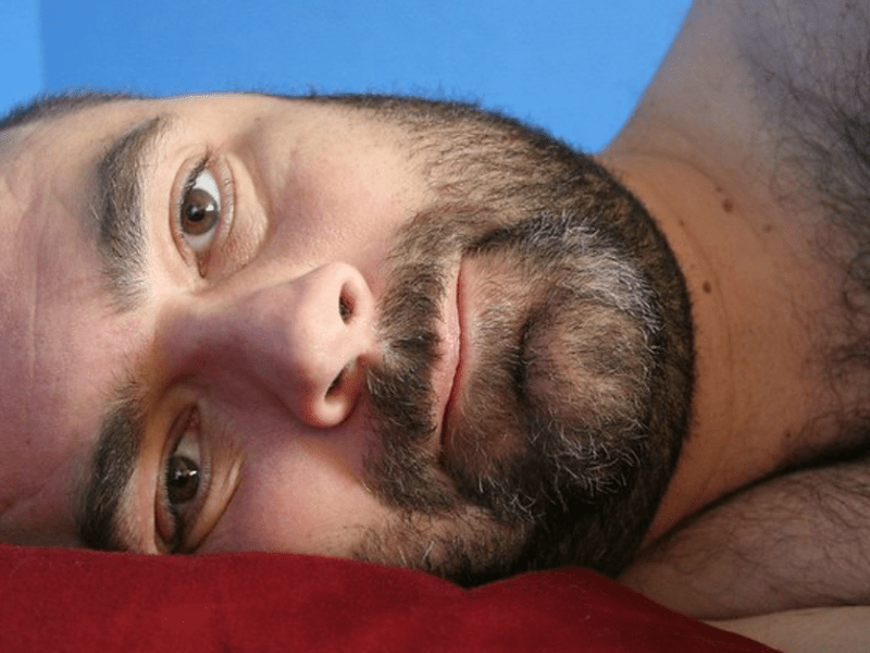 Mann liegt auf der Seite im Bett, sieht müde aus