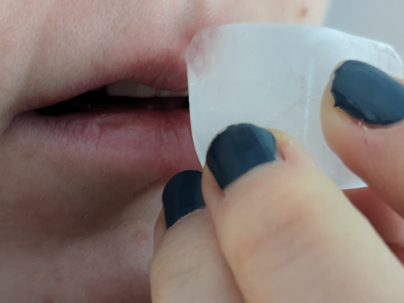 Ein Eiswürfel wird an den Mund gehalten, um Herpesbläschen zu bekämpfen.
