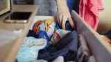 eine Frau räumt Wäsche in eine Schublade