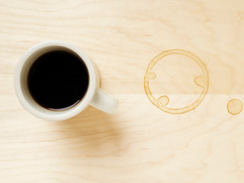 eine Tasse Tee steht auf dem Tisch, daneben ist ein Teerand auf der Tischplatte