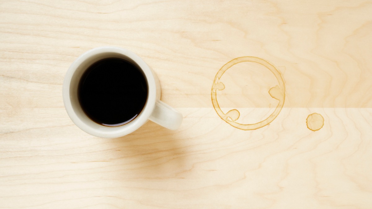 eine Tasse Tee steht auf dem Tisch, daneben ist ein Teerand auf der Tischplatte