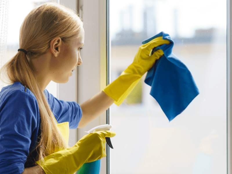 Eine Frau putzt ein Fenster.
