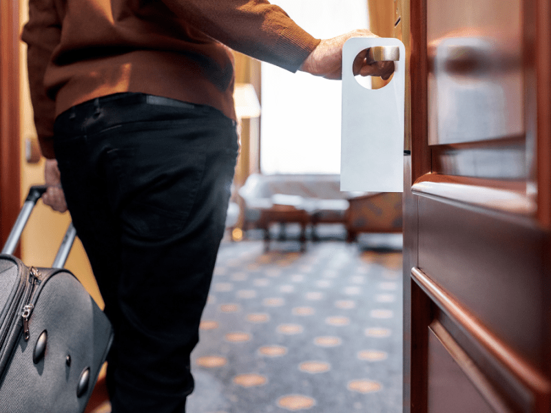 Ein Mann betritt mit Koffer ein Hotelzimmer.
