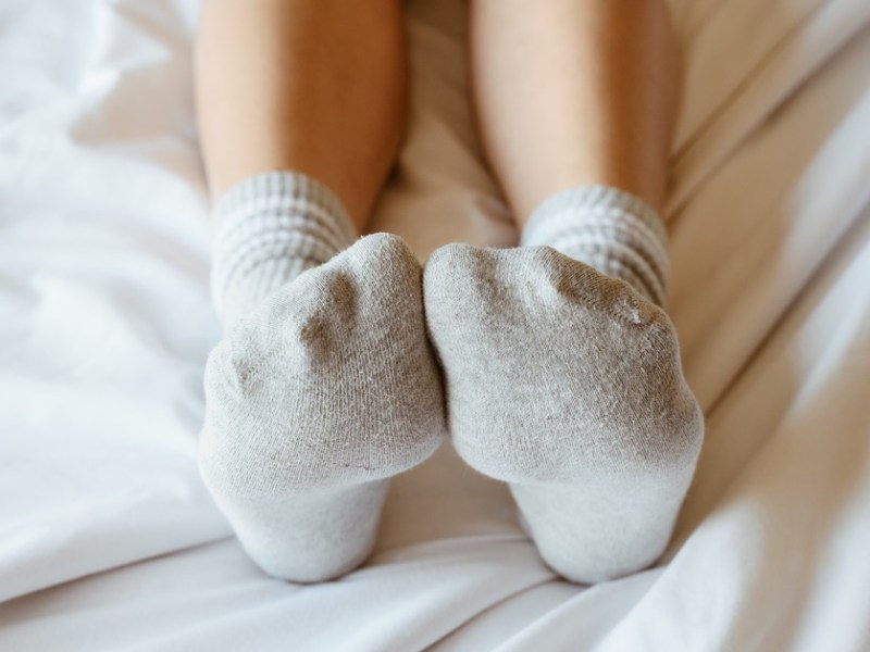 Frau liegt im Bett und hat Socken an.